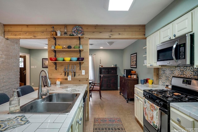 kitchen featuring white cabinets, sink, stainless steel appliances, and tile counters