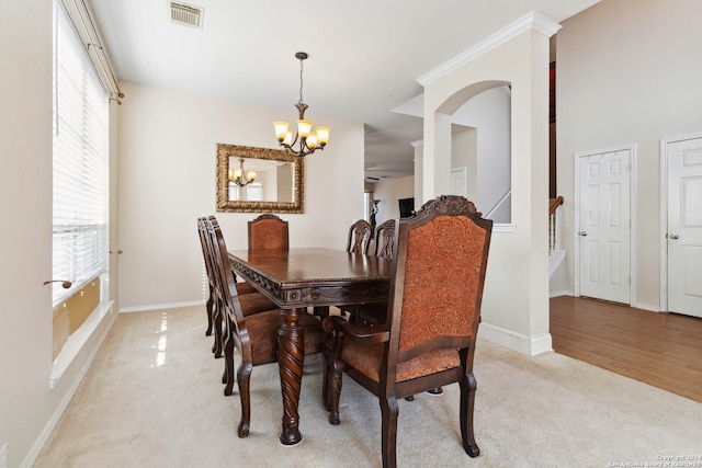 dining room with light carpet, a healthy amount of sunlight, and an inviting chandelier