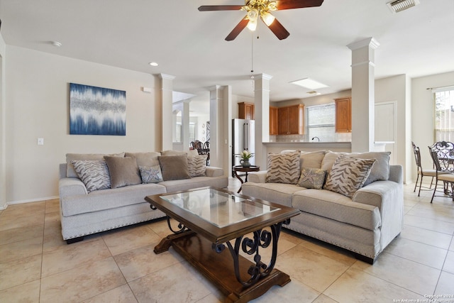 tiled living room featuring ceiling fan, decorative columns, and plenty of natural light