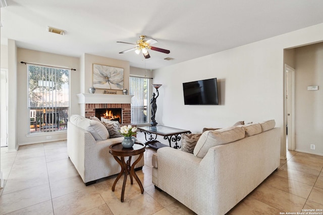 tiled living room with ceiling fan and a fireplace