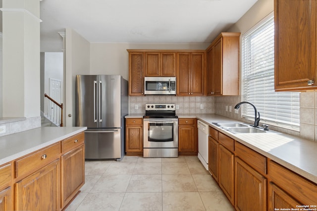 kitchen with sink, appliances with stainless steel finishes, light tile patterned flooring, and tasteful backsplash