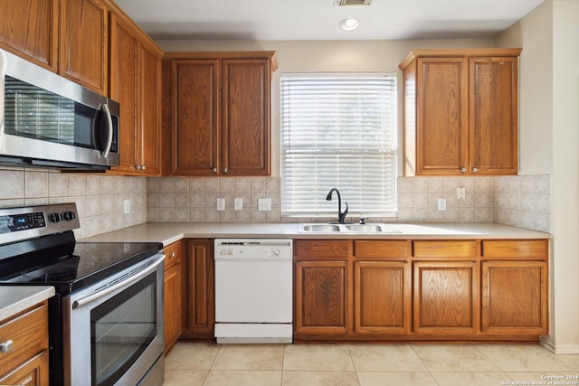 kitchen with sink, appliances with stainless steel finishes, decorative backsplash, and light tile patterned flooring