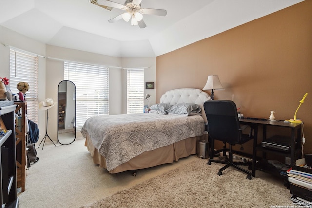 carpeted bedroom with a raised ceiling and ceiling fan