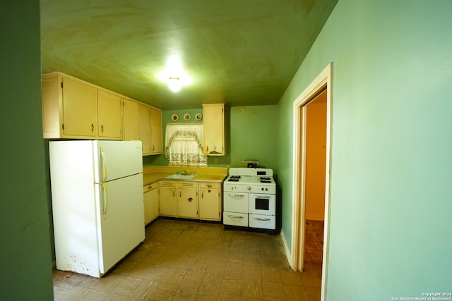 kitchen with white appliances, sink, and cream cabinetry