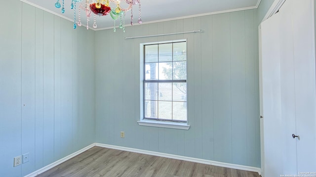 spare room featuring wood walls, wood-type flooring, and crown molding