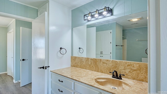 bathroom with vanity, ornamental molding, tasteful backsplash, hardwood / wood-style flooring, and toilet