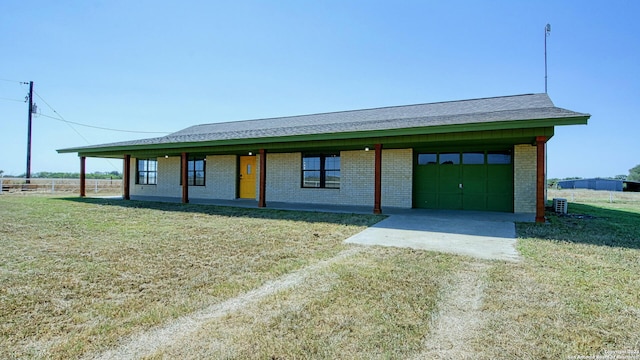 view of front facade featuring a front yard, cooling unit, and a garage