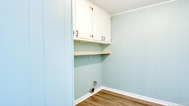 laundry area featuring wood walls, cabinets, crown molding, and hardwood / wood-style floors