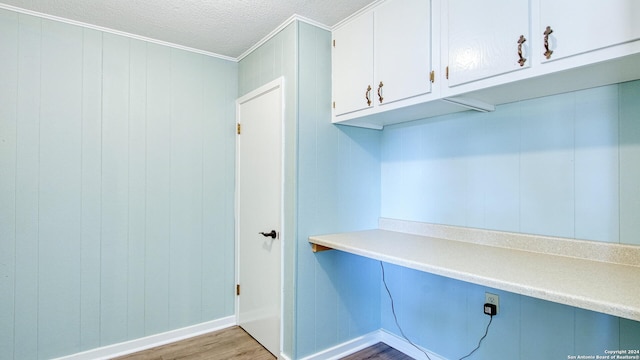 interior space featuring ornamental molding, a textured ceiling, wooden walls, and hardwood / wood-style floors