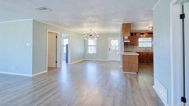 kitchen with tasteful backsplash, sink, light hardwood / wood-style floors, hanging light fixtures, and ornamental molding