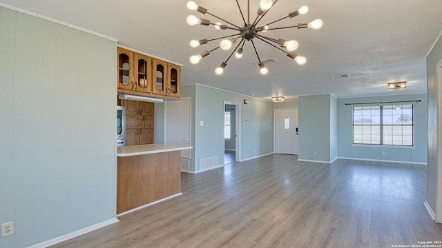 unfurnished living room with ornamental molding, hardwood / wood-style flooring, and a chandelier