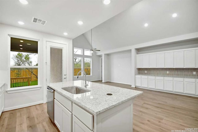 kitchen with white cabinets, sink, a kitchen island with sink, and light stone counters