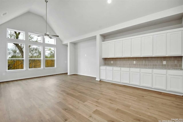 unfurnished living room with high vaulted ceiling, ceiling fan, and light hardwood / wood-style flooring