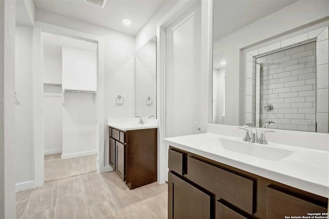 bathroom featuring tiled shower and vanity