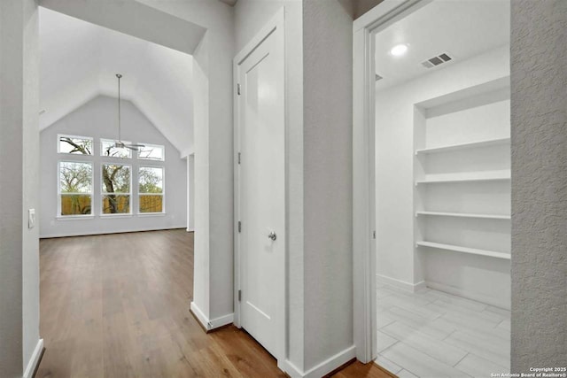 corridor with lofted ceiling, light hardwood / wood-style flooring, and built in features