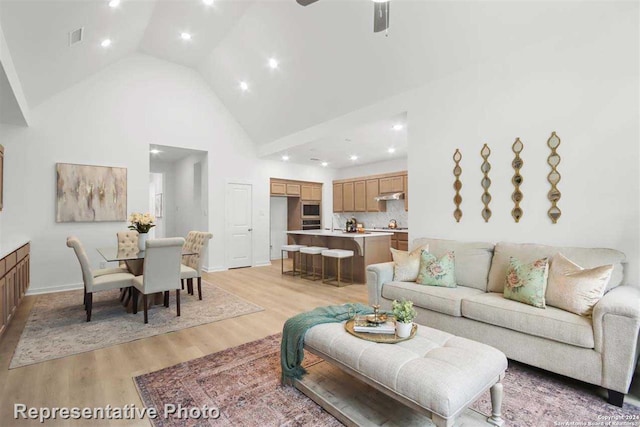 living room with high vaulted ceiling, ceiling fan, and light hardwood / wood-style floors