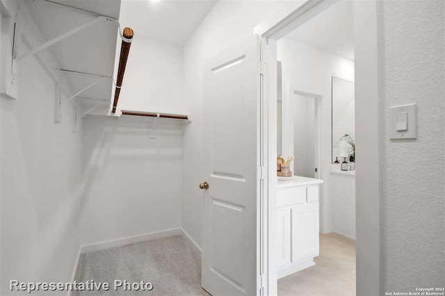 walk in closet featuring light colored carpet