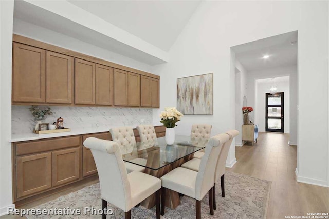 dining space featuring high vaulted ceiling and light hardwood / wood-style flooring