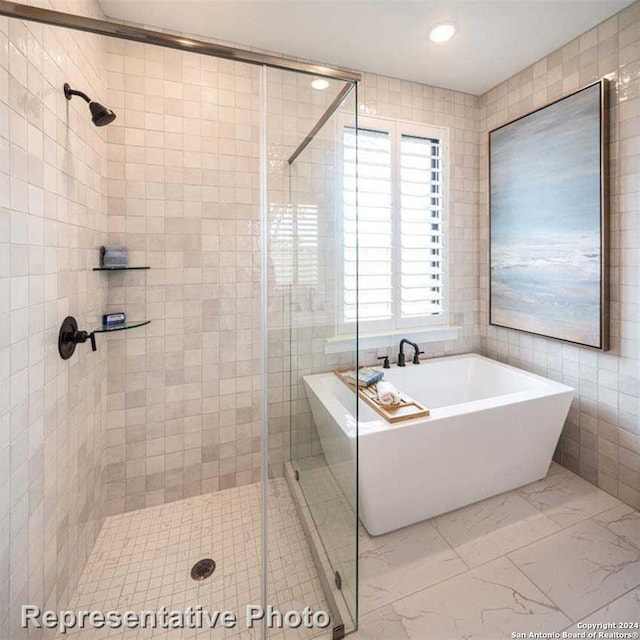 bathroom with separate shower and tub and tile walls