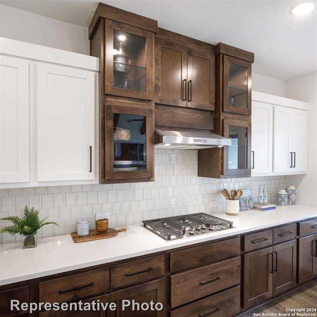 kitchen featuring extractor fan, white cabinets, stainless steel gas cooktop, and dark brown cabinets