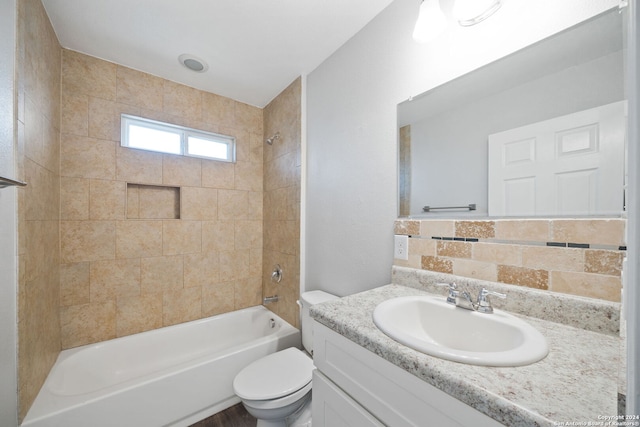 full bathroom with tiled shower / bath, vanity, toilet, and decorative backsplash