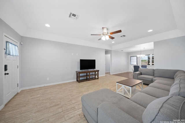 living room with ceiling fan with notable chandelier and light wood-type flooring