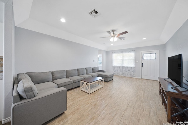 living room featuring light hardwood / wood-style floors, a tray ceiling, and ceiling fan