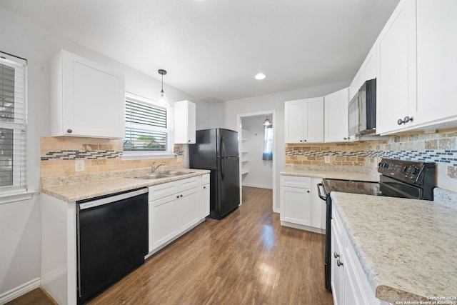 kitchen featuring hanging light fixtures, sink, white cabinetry, black appliances, and hardwood / wood-style floors