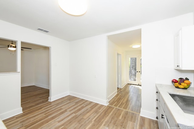 interior space featuring a sink, visible vents, ceiling fan, light wood-style floors, and baseboards