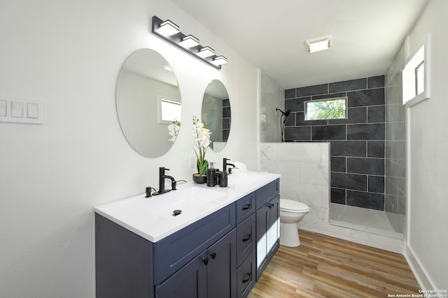 bathroom with vanity, toilet, hardwood / wood-style flooring, and a tile shower