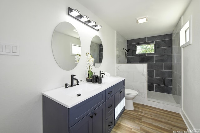 full bathroom with a sink, double vanity, toilet, a walk in shower, and wood finished floors