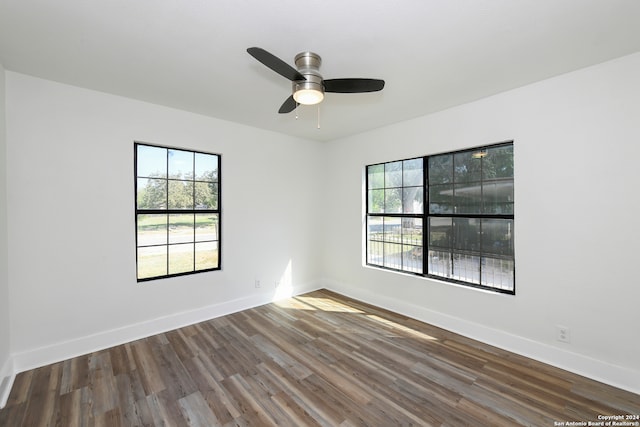 unfurnished room featuring ceiling fan, a healthy amount of sunlight, and dark hardwood / wood-style floors