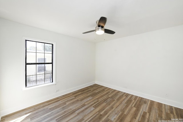 empty room featuring wood finished floors, a ceiling fan, and baseboards