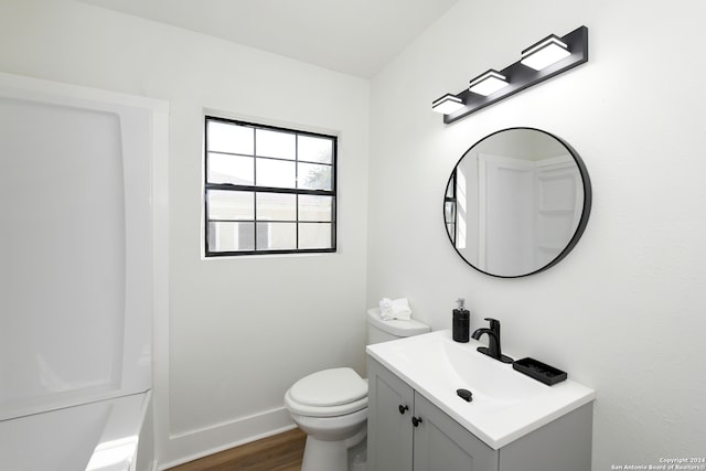 bathroom with vanity, toilet, a tub to relax in, and hardwood / wood-style floors