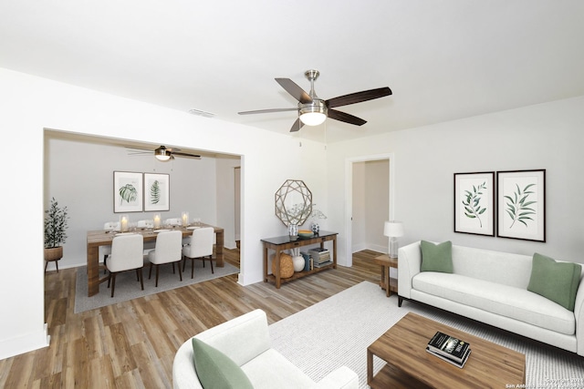 living area featuring visible vents, ceiling fan, and light wood-style flooring