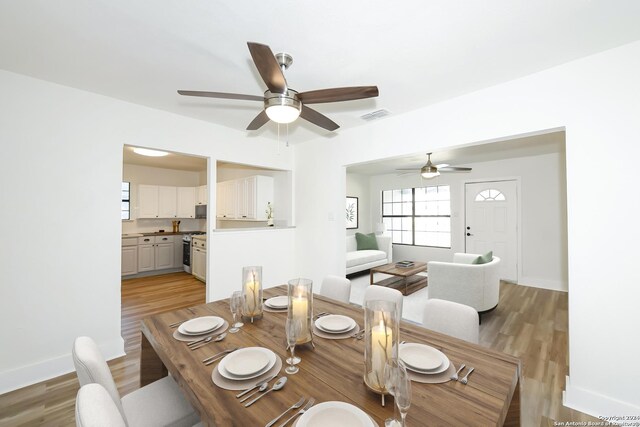 dining space with baseboards, visible vents, ceiling fan, and light wood-type flooring
