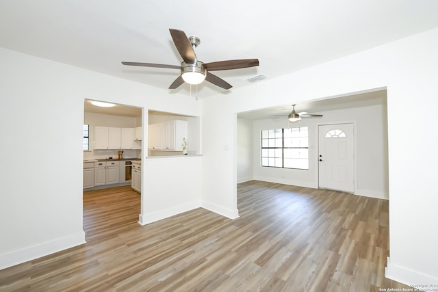 unfurnished living room with baseboards, visible vents, ceiling fan, and light wood-style flooring