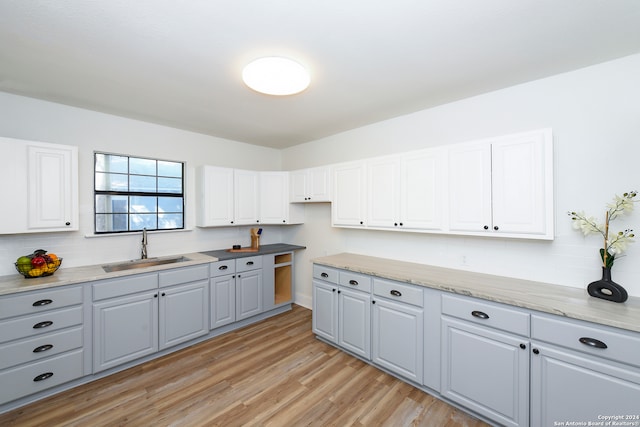 kitchen featuring decorative backsplash, sink, light wood-type flooring, gray cabinets, and white cabinetry