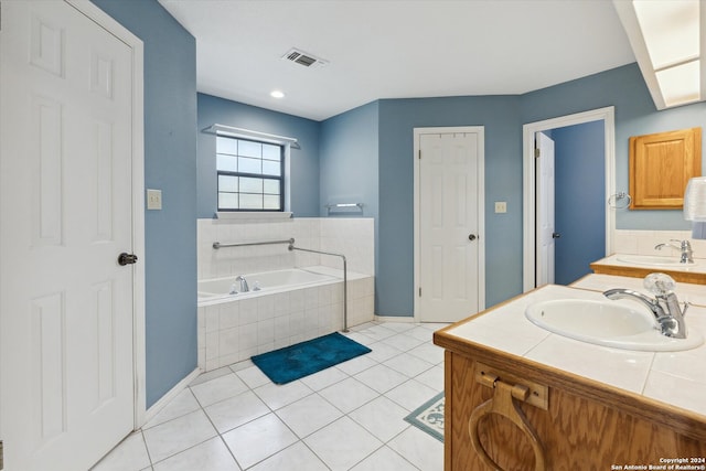 bathroom with tiled tub, tile patterned floors, and vanity