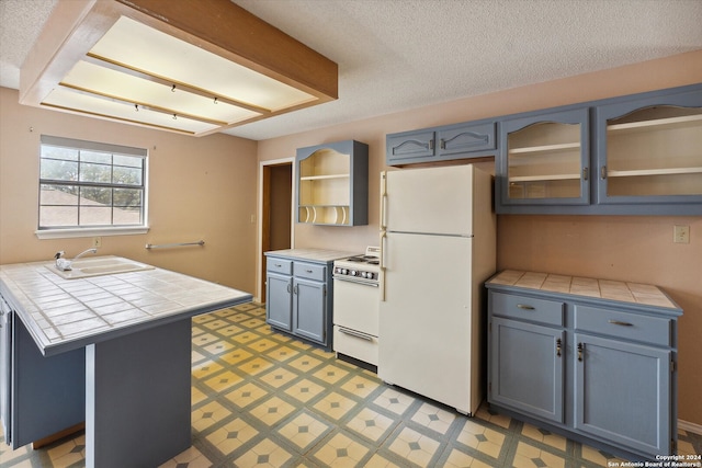 kitchen with white appliances, a kitchen breakfast bar, sink, tile countertops, and a textured ceiling