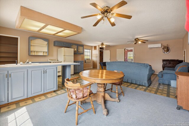 dining area featuring an AC wall unit, sink, and a textured ceiling