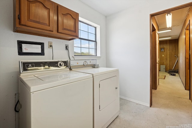 washroom with cabinets, wooden walls, and washing machine and clothes dryer