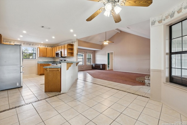 kitchen featuring a center island, a breakfast bar, vaulted ceiling, appliances with stainless steel finishes, and light tile patterned floors