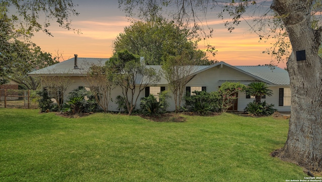 back house at dusk featuring a yard