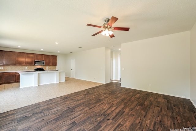 unfurnished living room featuring ceiling fan and wood-type flooring