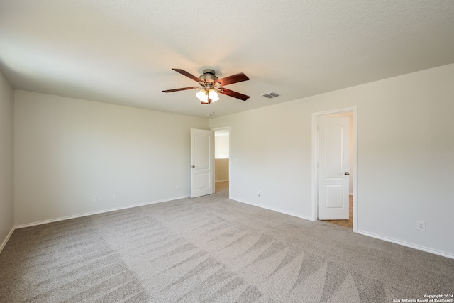 spare room featuring light carpet, a textured ceiling, and ceiling fan