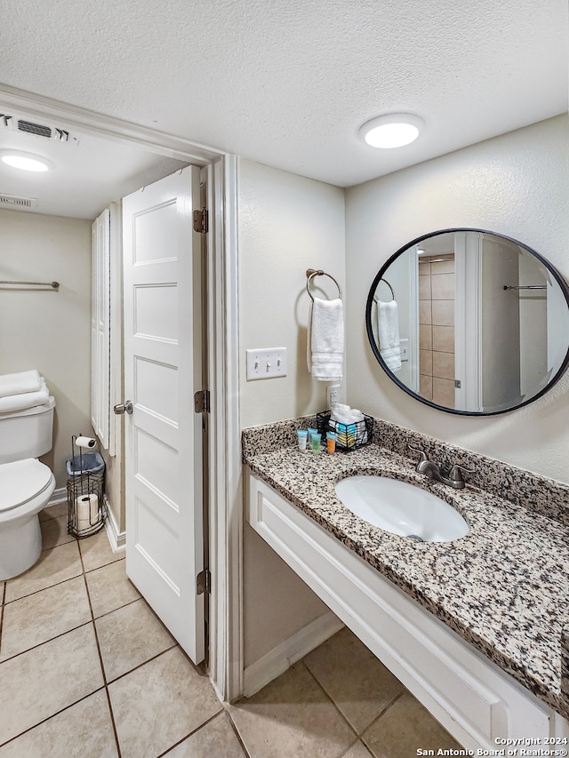 bathroom featuring tile patterned floors, vanity, toilet, and a textured ceiling