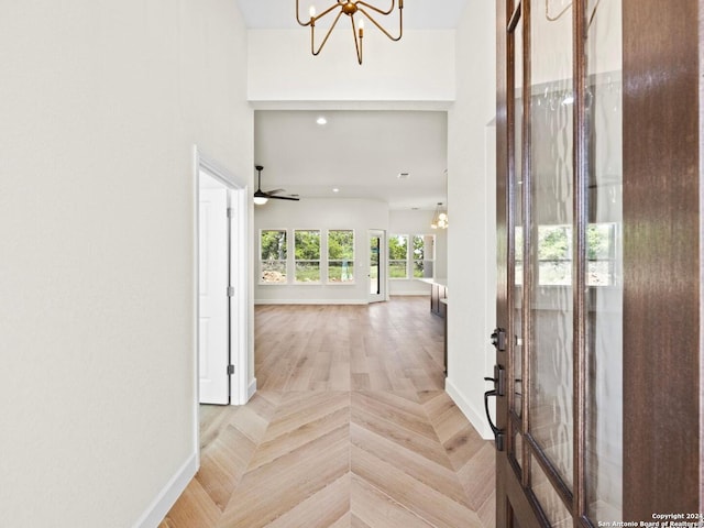 foyer entrance with ceiling fan with notable chandelier and light parquet floors