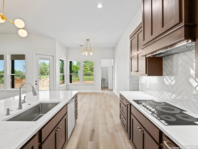 kitchen featuring pendant lighting, sink, black stovetop, light stone countertops, and stainless steel dishwasher