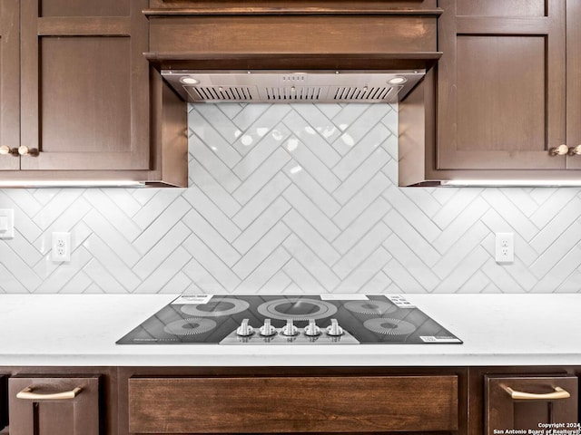 kitchen featuring black electric stovetop, decorative backsplash, and premium range hood